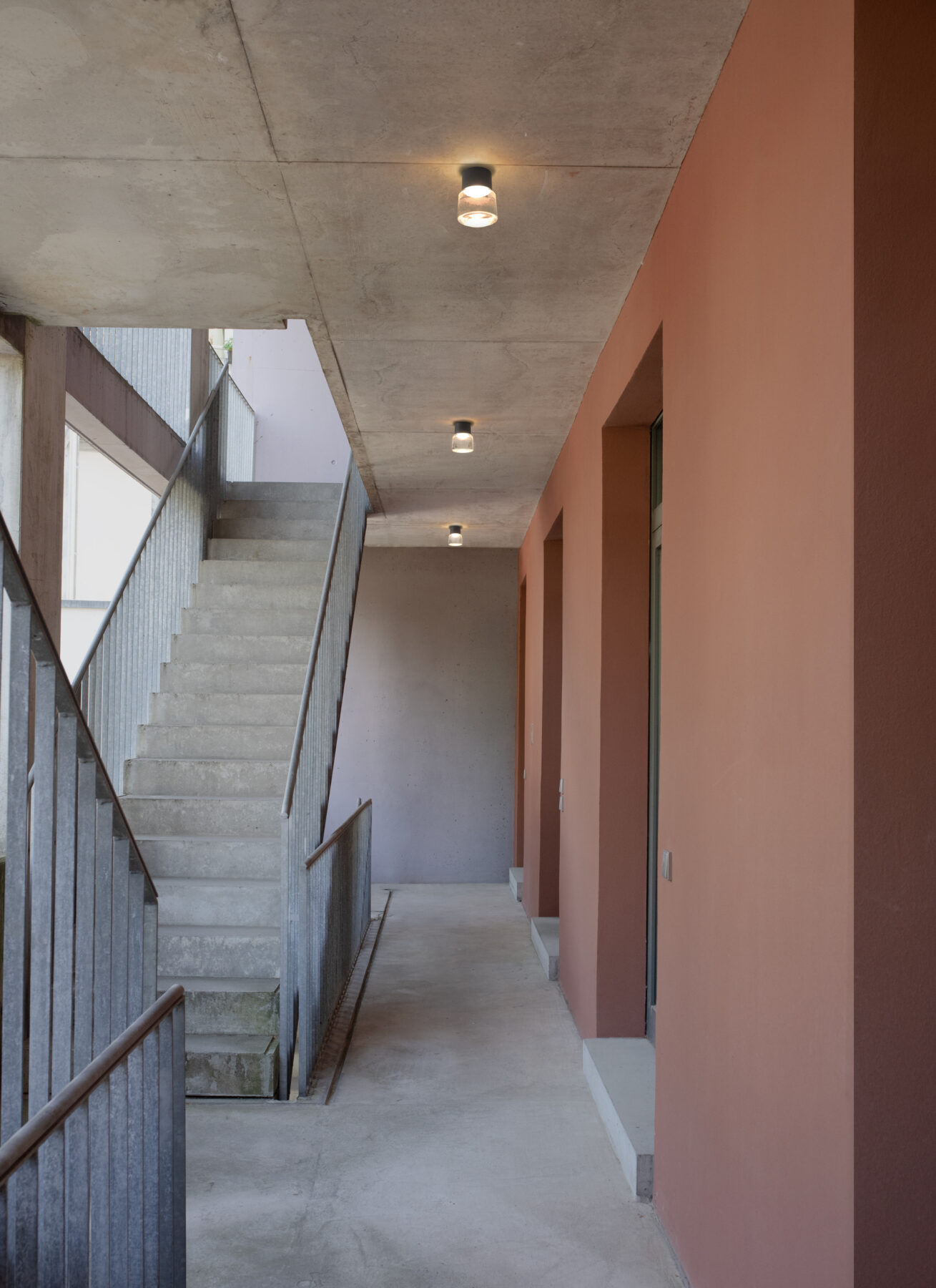 Die handgefertigte Gussglas-Leuchte CAST M mit schwarzem Aluminiumaufbau als Außenbeleuchtung aufgereiht im modernen Treppenhaus.